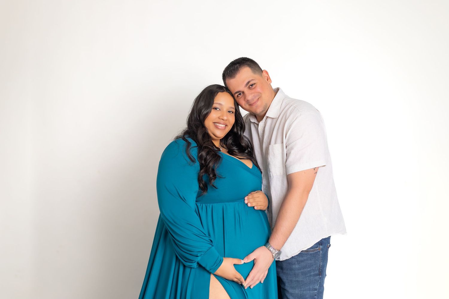 Pregnant woman in elegant off-shoulder light blue tulle maternity gown posing gracefully against a neutral beige background.