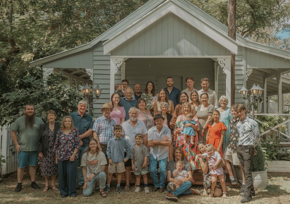 Large extended family group portrait on porch of charming blue cottage.