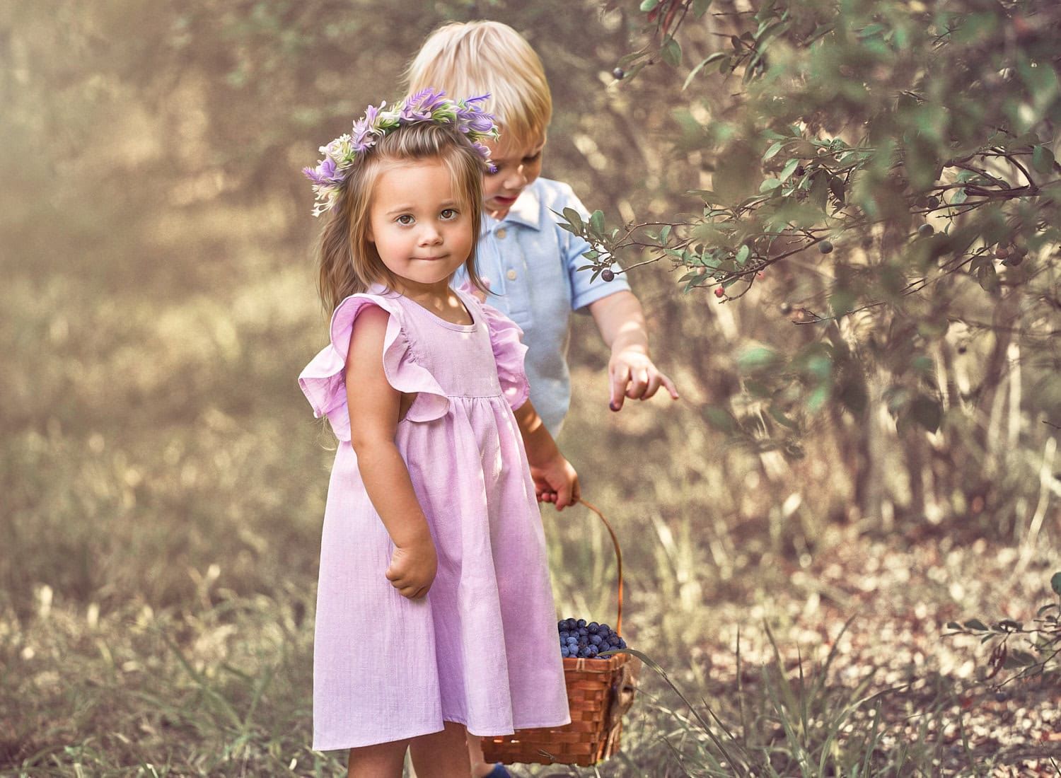 Toddler girl in lavender dress with toddler boy dropping a blueberry in basket