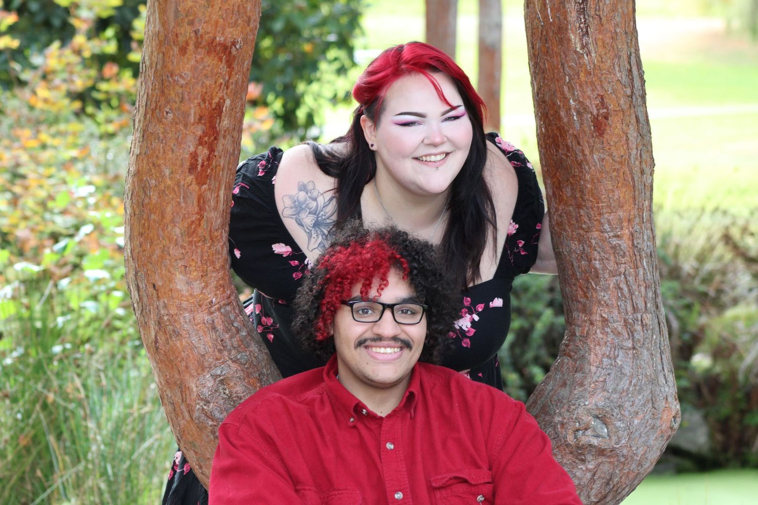 Couple posing together between trees, smiling during outdoor portrait session