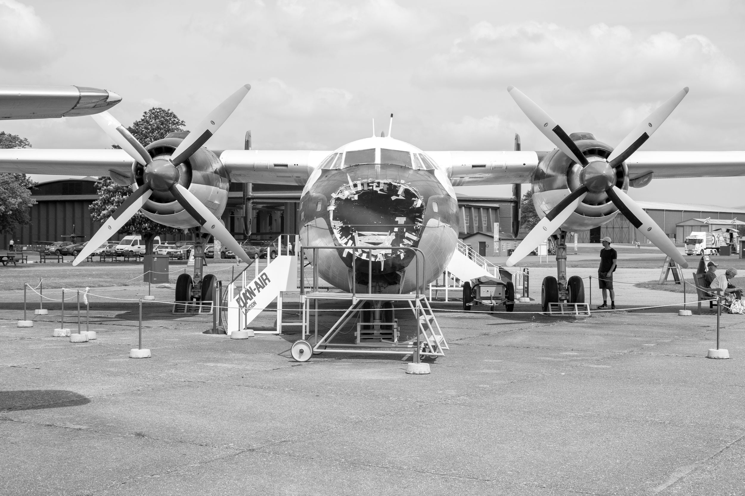 Vintage black and white photo of a large propeller aircraft on display outdoors at an airshow.