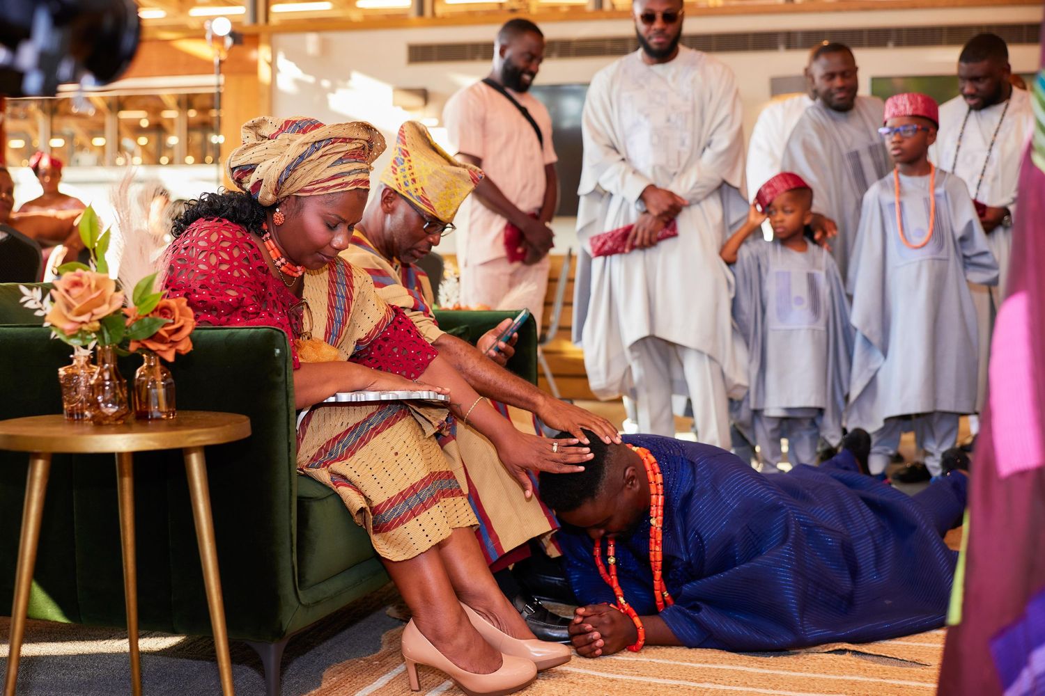 Traditional African wedding ceremony with colorful attire, as a man prostrates before a woman in respect.