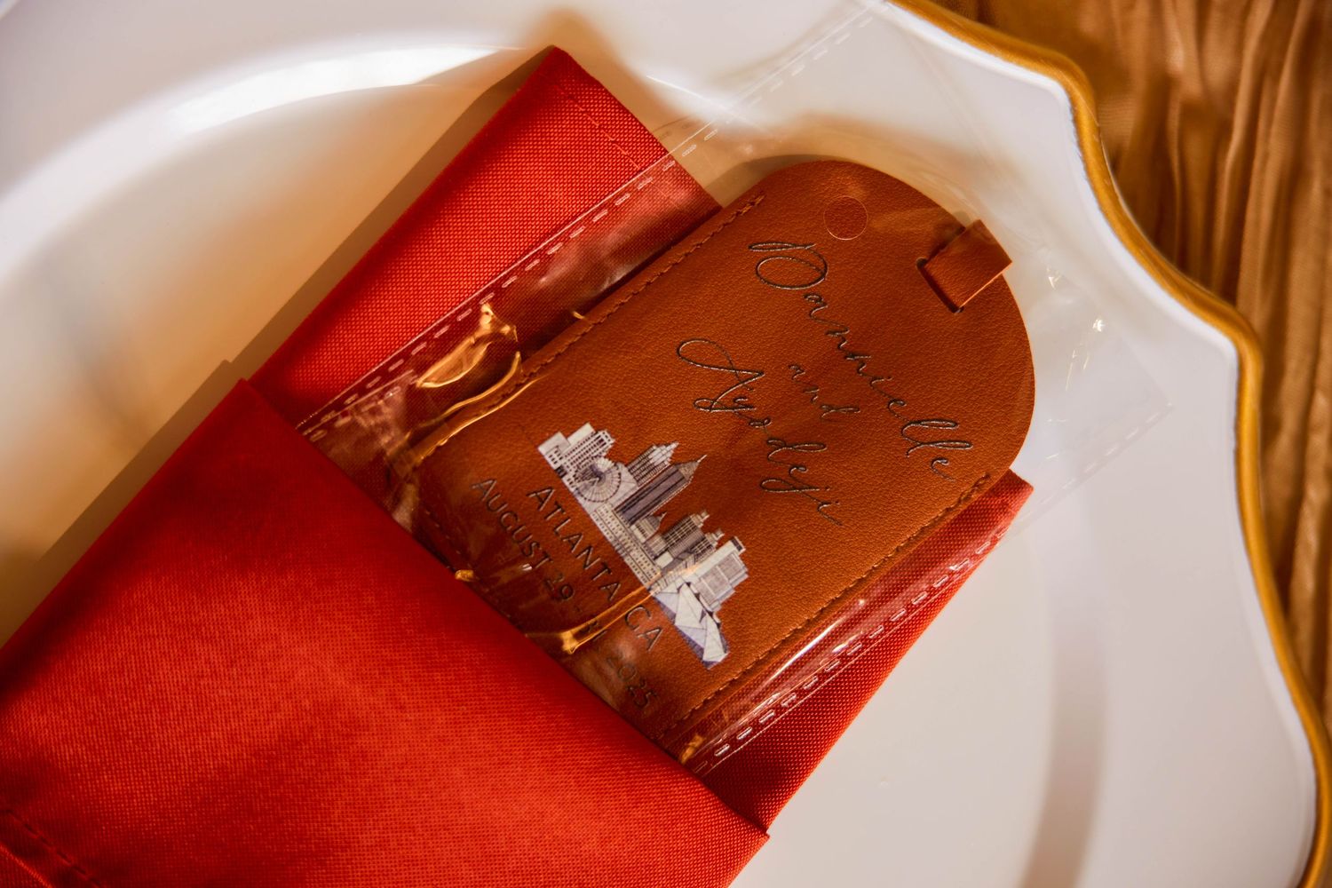 Elegant leather wedding menu with crystal church emblem on red silk napkin at a formal reception table setting.
