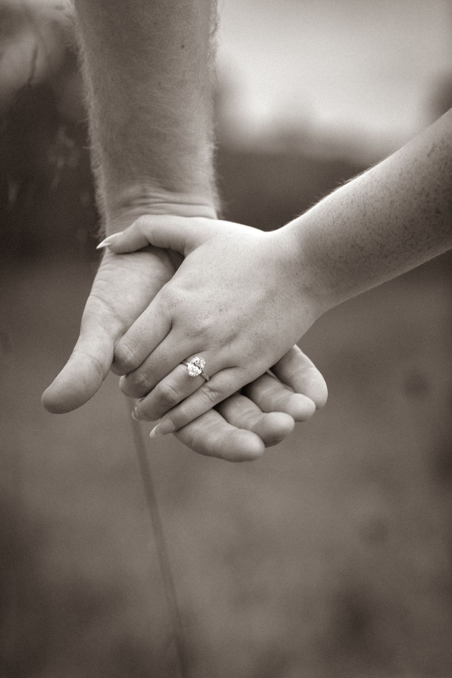 A series of sepia-toned close-up photos showing two hands holding each other with an engagement ring visible.