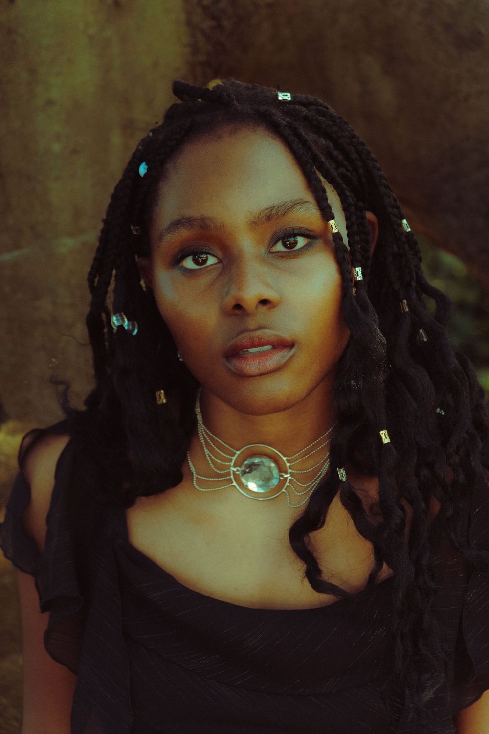 Ethereal portrait of a Black woman with shiny jewelry and long black hair, gazing dreamily into the camera.