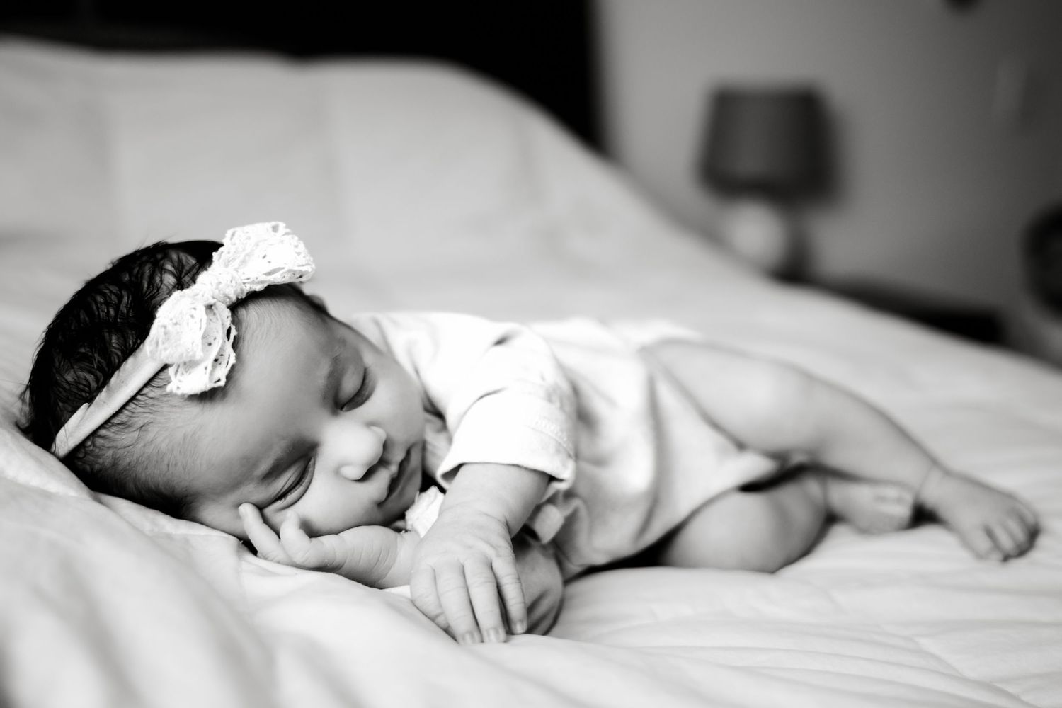 Black and white photo of sleeping baby with lace headband.