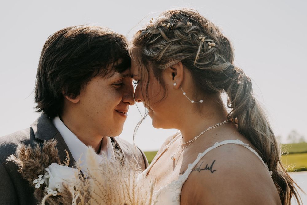 A romantic couple embraces in golden sunlight during a wedding photo session in a scenic outdoor setting.