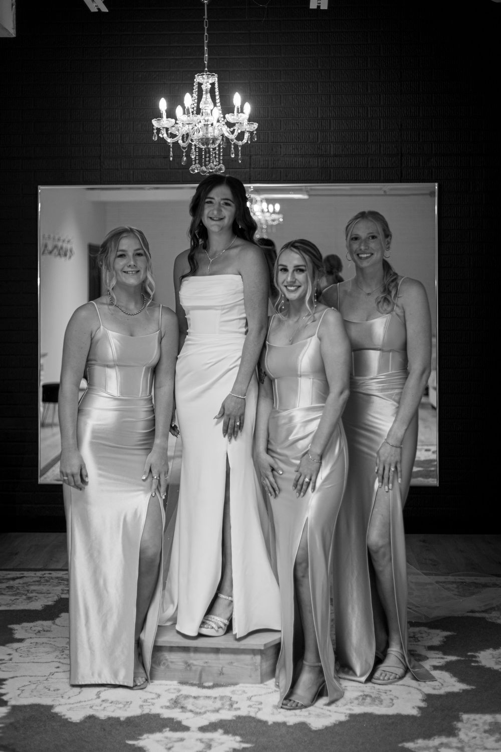 Black and white photo series showing bridesmaids in light-colored dresses posing under elegant chandeliers.