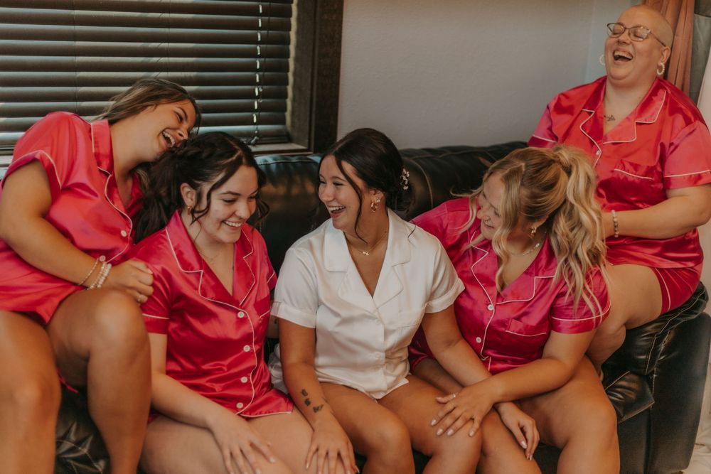 Candid moment of wedding party laughing together on couch in matching robes.