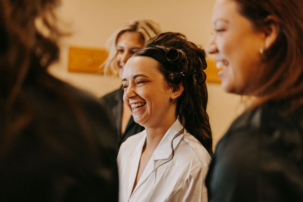 A group of people share a candid laughing moment together while wearing white robes.