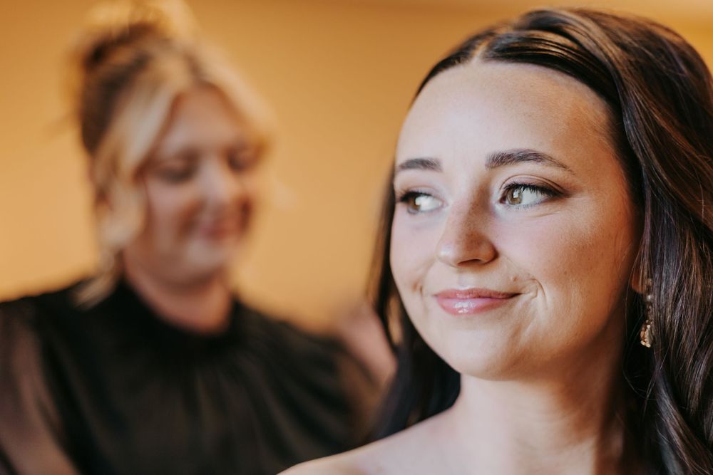 A bride smiles joyfully during wedding preparations while getting ready for her special day.