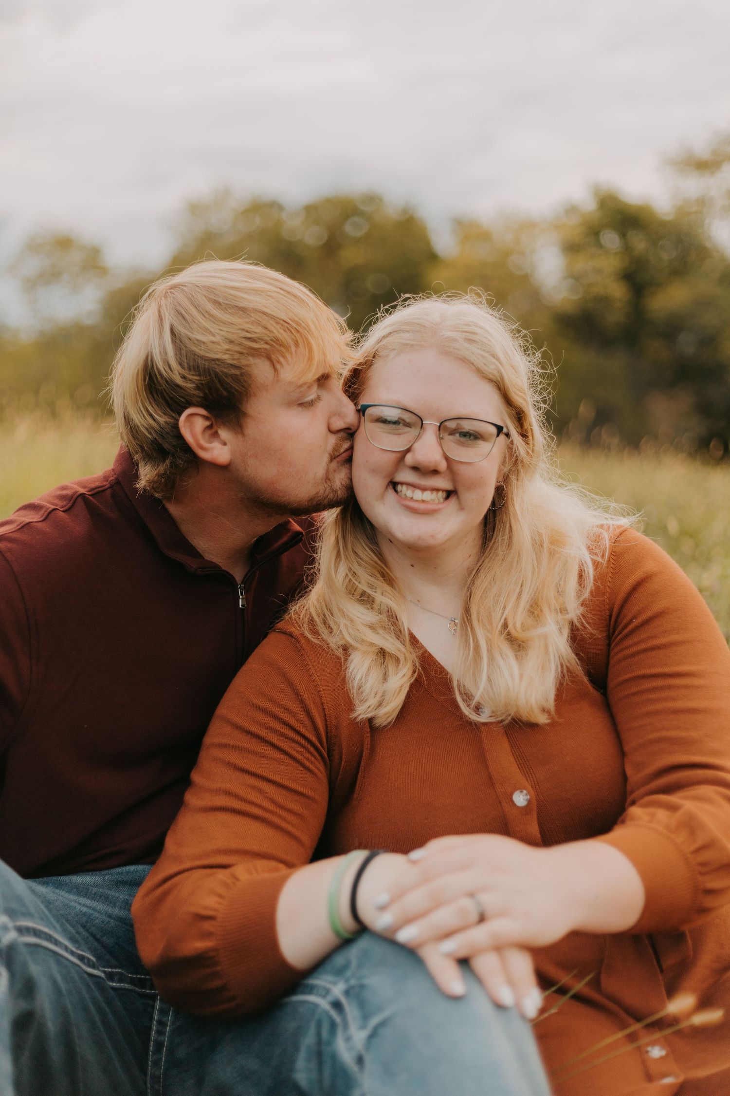 Couple sharing affectionate moment while sitting in autumn field.