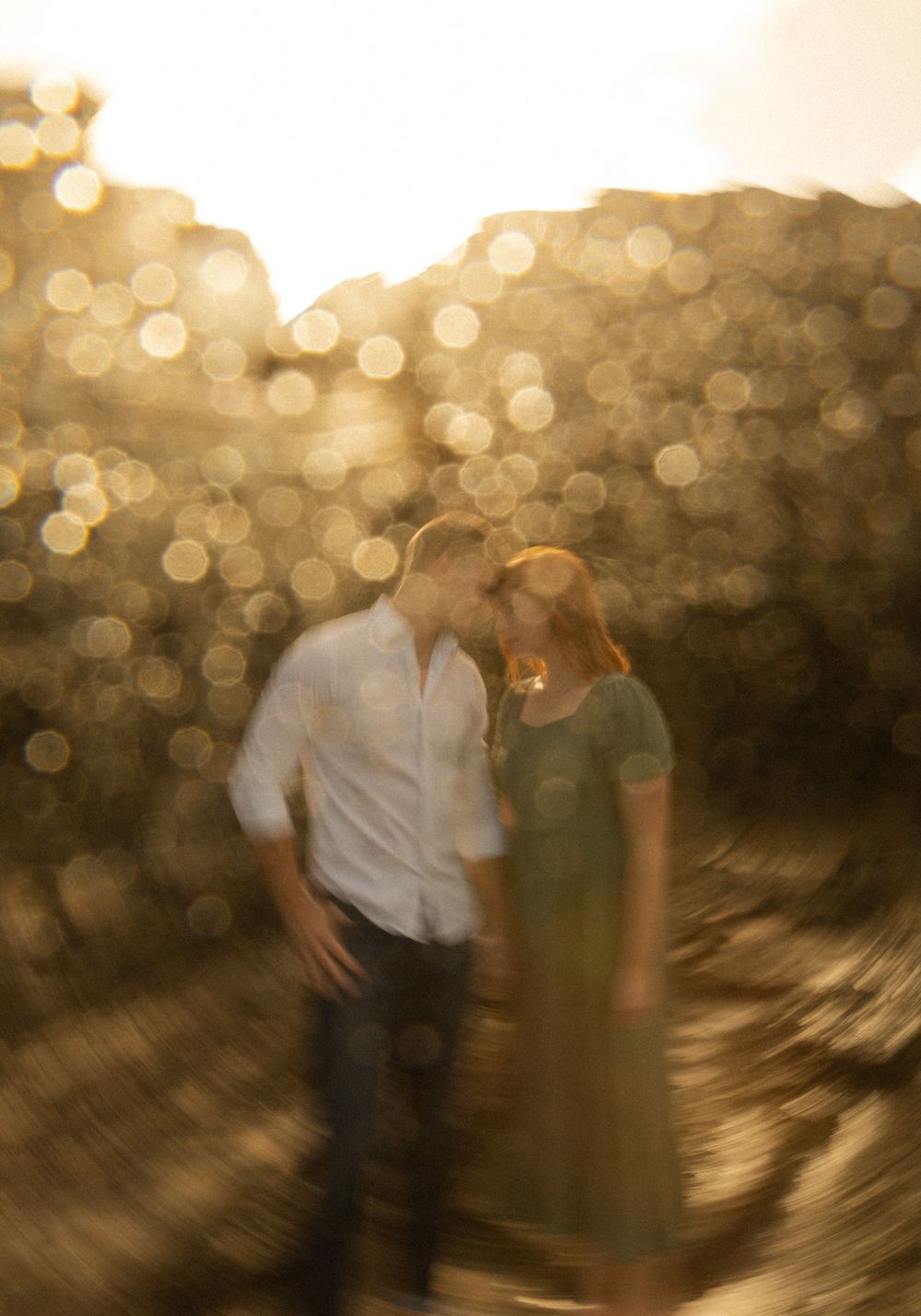 A dreamy sunset photo of a couple with golden bokeh lights in the background.