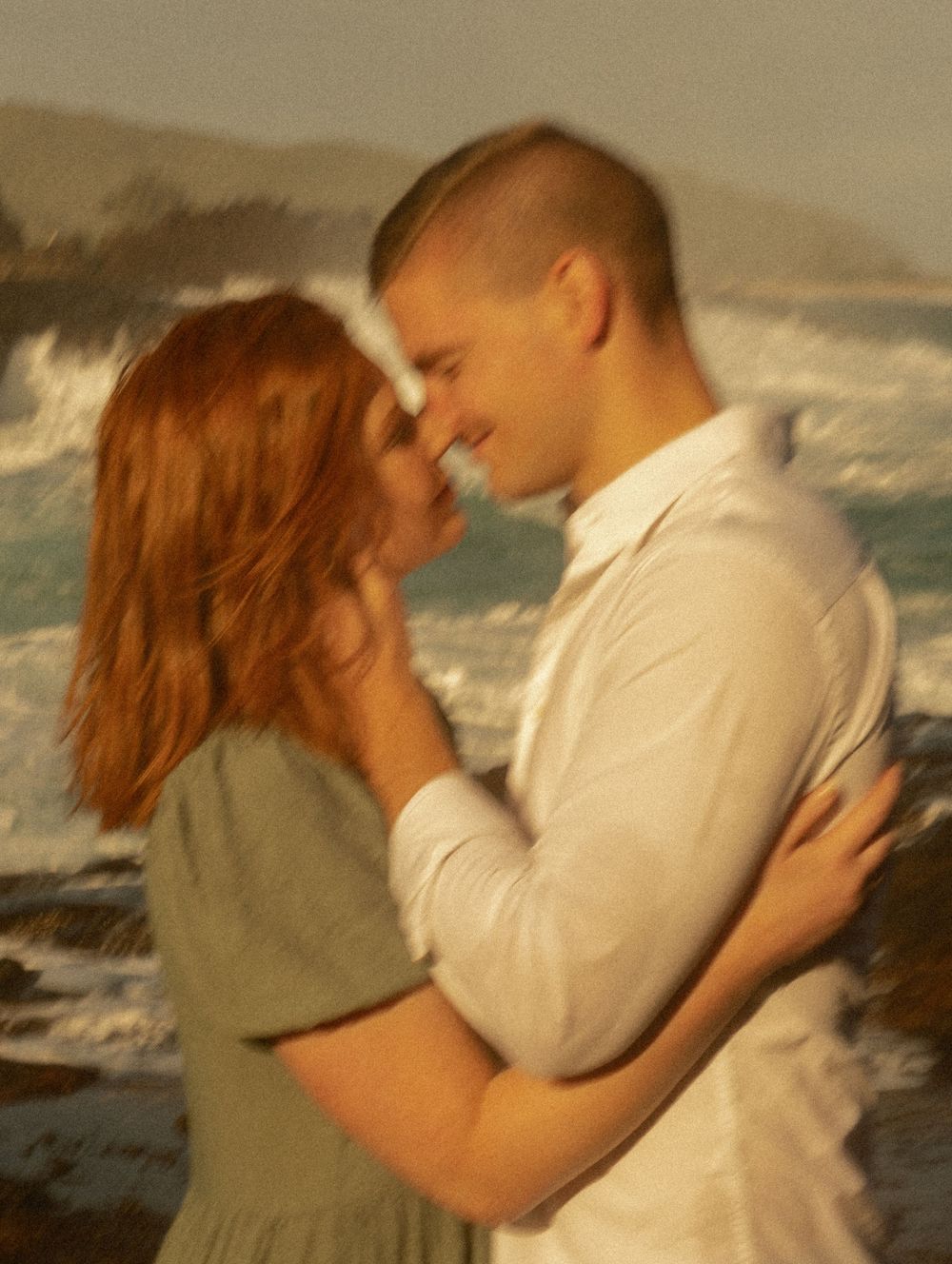 A tender embrace against a backdrop of crashing ocean waves.