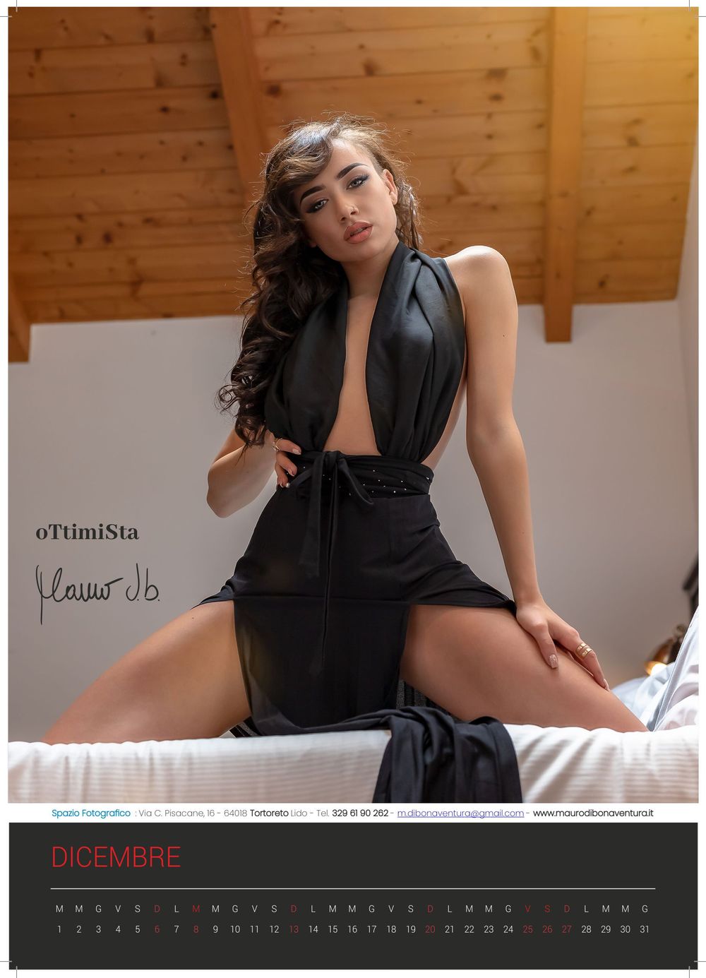 Fashion portrait on bed featuring a dramatic black halter dress design.
