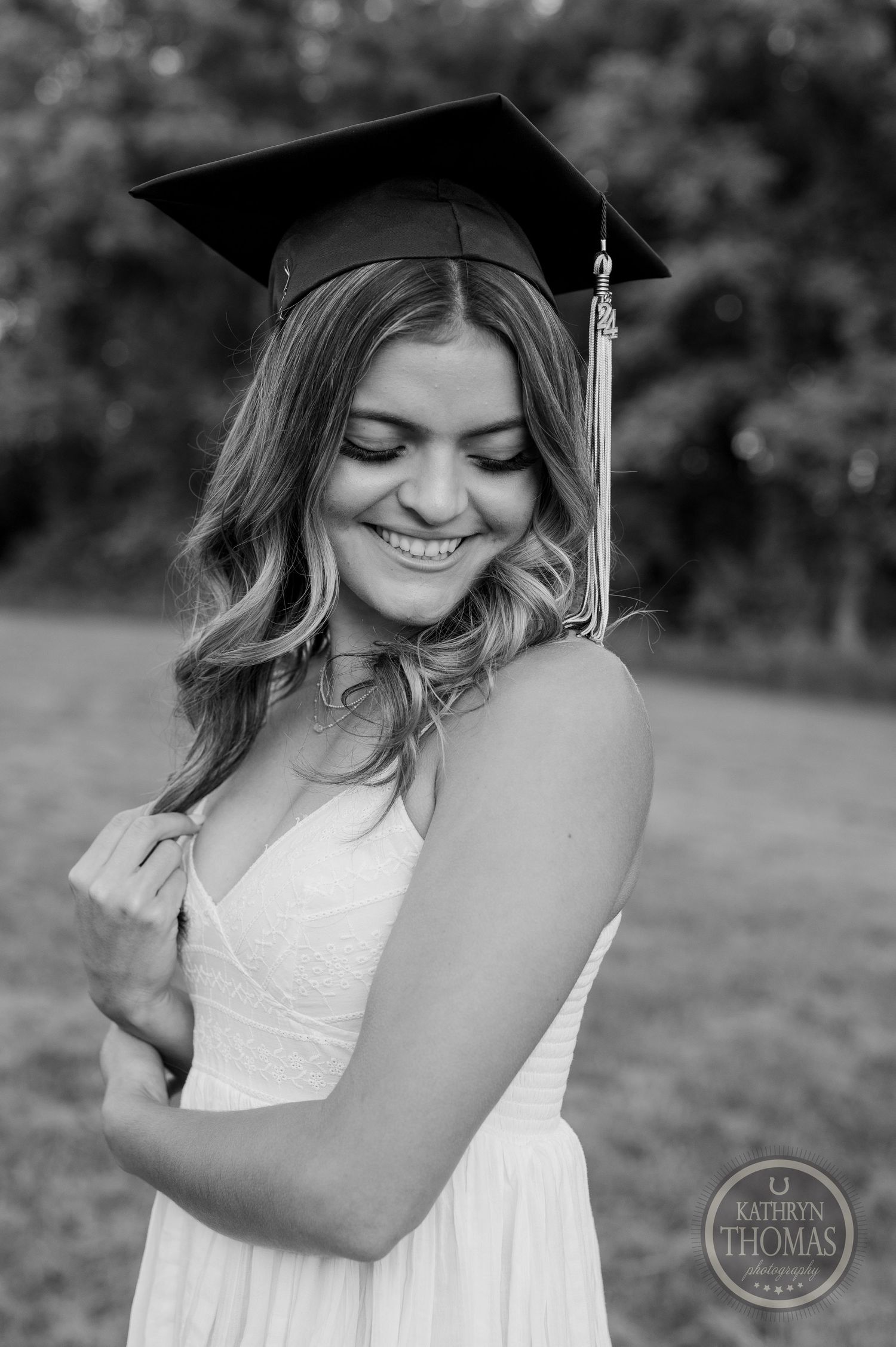 Black and white portrait of graduate in cap with eyes closed and joyful expression.