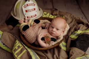 A series of newborn baby photos featuring firefighter gear and equipment arranged artistically in a collage.