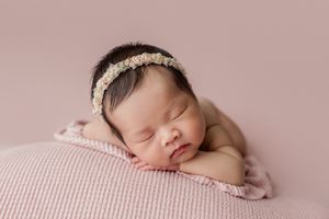 Collage of newborn baby sleeping peacefully on soft pink fabric in various poses during professional photo session.