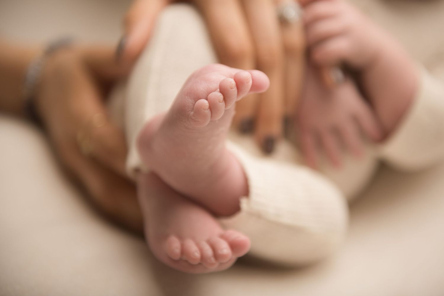 Close-up view of tiny newborn baby feet against a soft beige background.