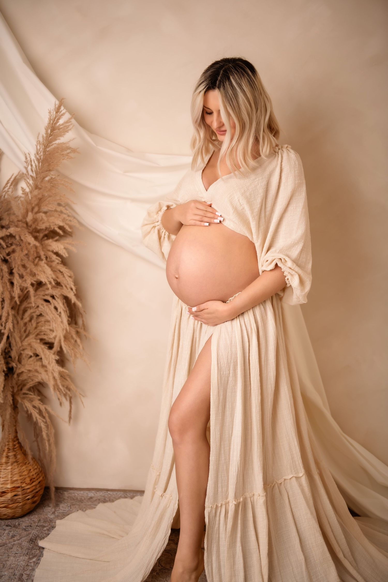 A maternity photoshoot featuring a soft maternity client closet dress against a neutral backdrop with soft lighting.