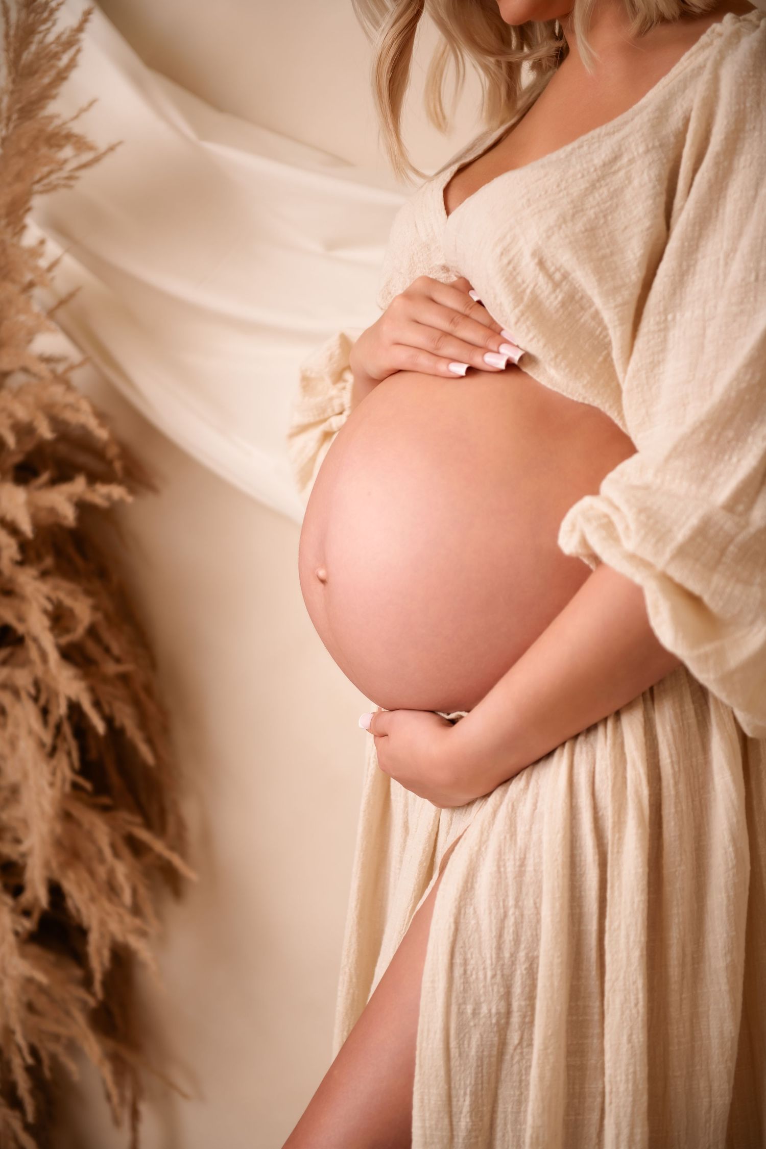 A series of artistic maternity photos showing a pregnancy bump in a white flowing dress against a neutral background.