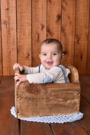 Baby portrait session with rustic wooden box and lace doily on wood plank background.