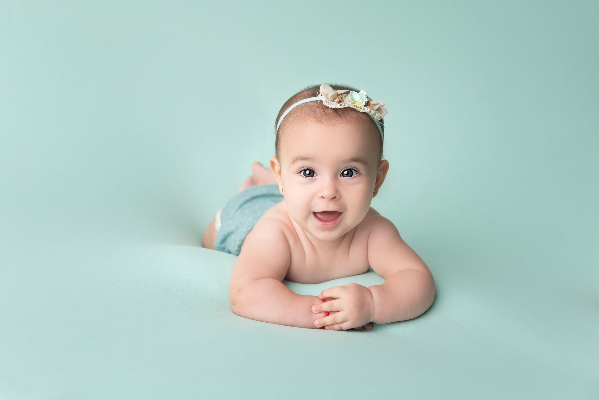 Baby in mint green setting during professional milestone photography session.