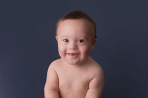 Cheerful baby portrait against dark navy background during studio session.