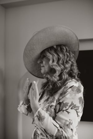 Elegant figure in a wide-brimmed hat and floral dress shown in black and white photography.