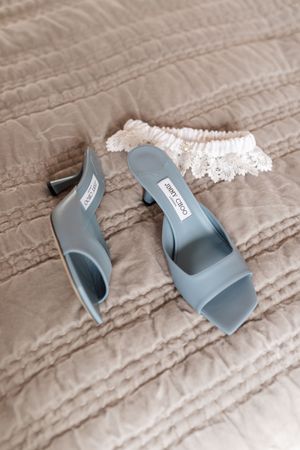 A pair of light blue wedding shoes arranged in a sequence on a textured beige fabric surface.