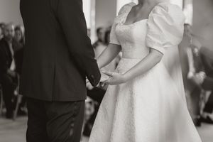 A couple holding hands during their wedding ceremony, in lack and white.