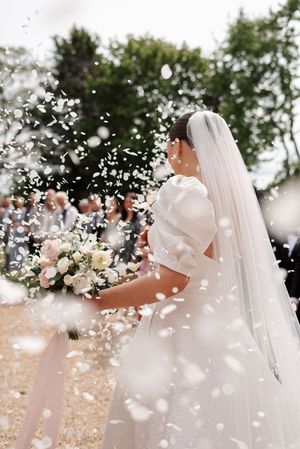 White flower petals float through the air during confetti with floral arrangements.
