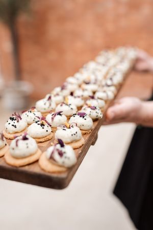 Elegant mini desserts topped with whipped cream and chocolate sprinkles arranged on a wooden serving board.