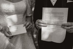 A black and white photo showing a couple holding their wedding vows during a private ceremony.