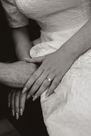 Close-up shots of hands with an engagement ring resting on white lace wedding dress fabric.