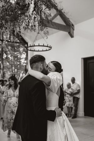 Black and white wedding reception photos showing dancing and embraces under a modern chandelier.
