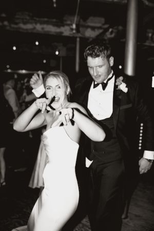 Black and white candid photo of couple dancing and having fun at wedding reception.