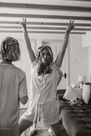 Black and white photo sequence showing a person in a striped top playfully jumping and dancing around a couch.