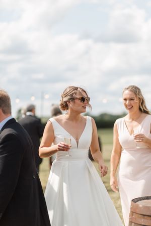 Wedding party laughs together in a candid moment outdoors on a cloudy summer day.