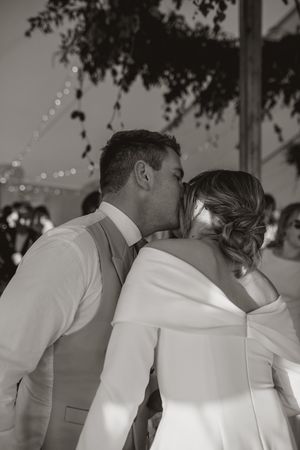 A tender moment shared between a couple during their wedding celebration under twinkling lights.