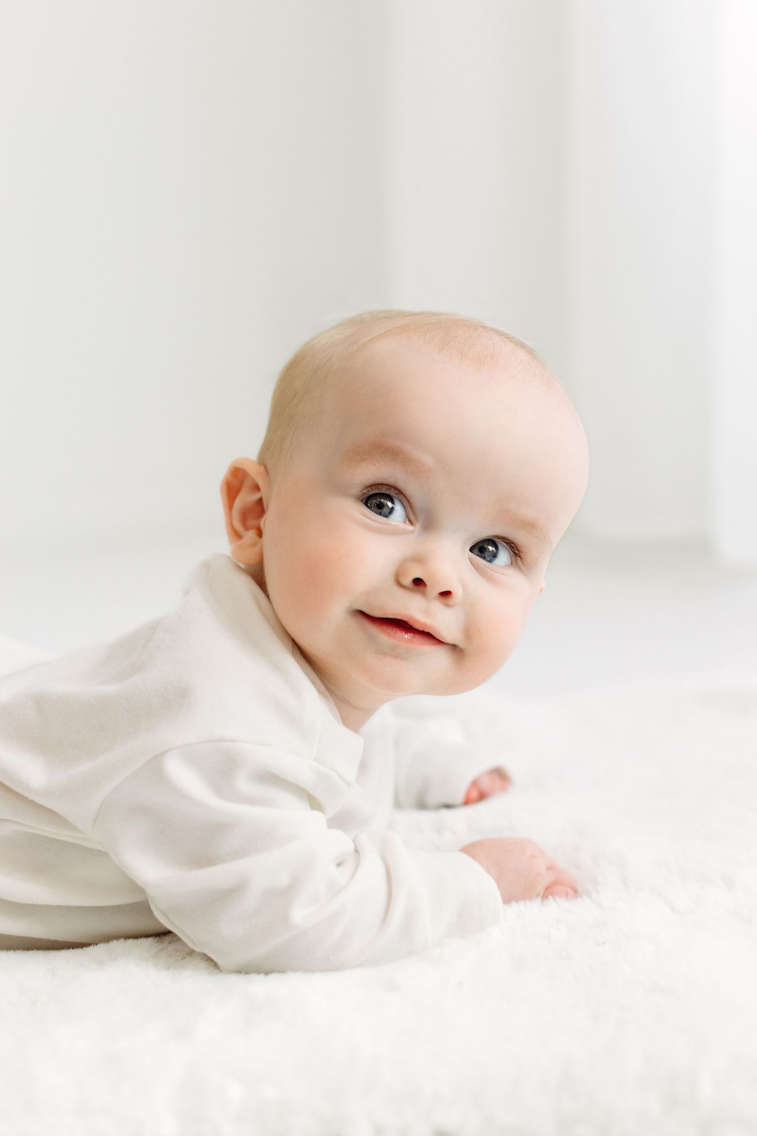 Curious 6 month old boy in white sweater, looking up to the left