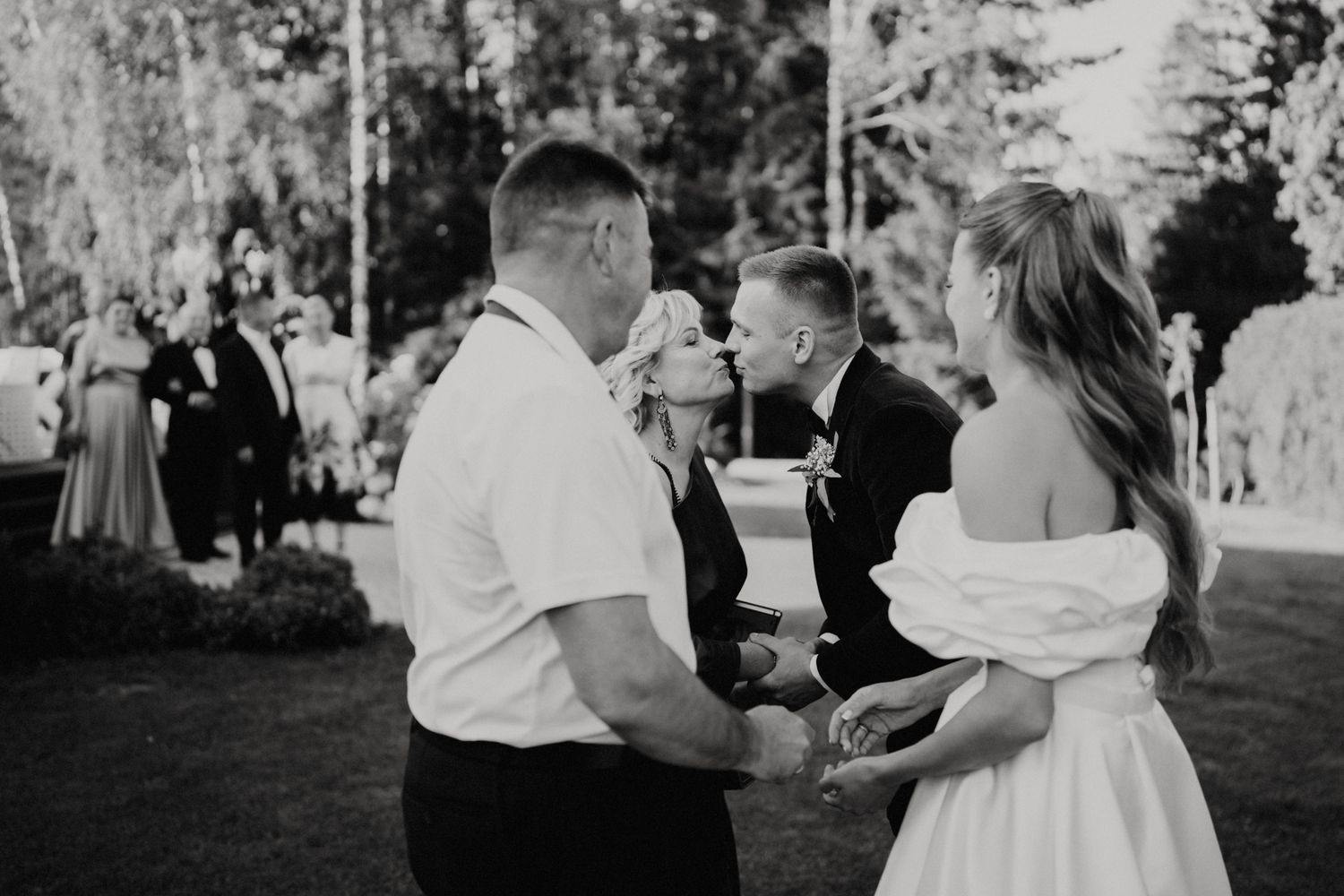 Black and white photo shows wedding party members enjoying drinks at outdoor reception.