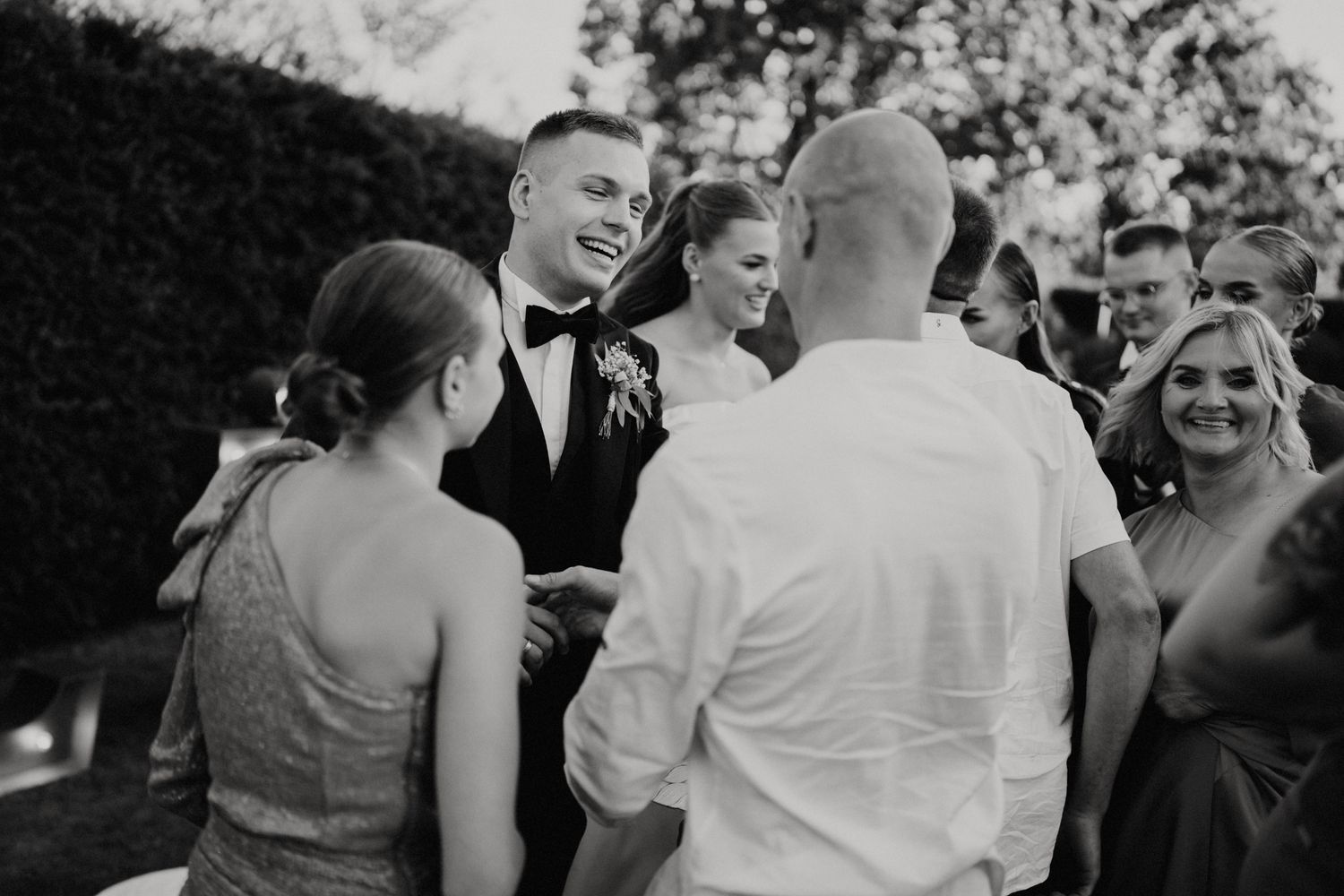 Wedding guests dancing and celebrating at an outdoor reception with joyful expressions.