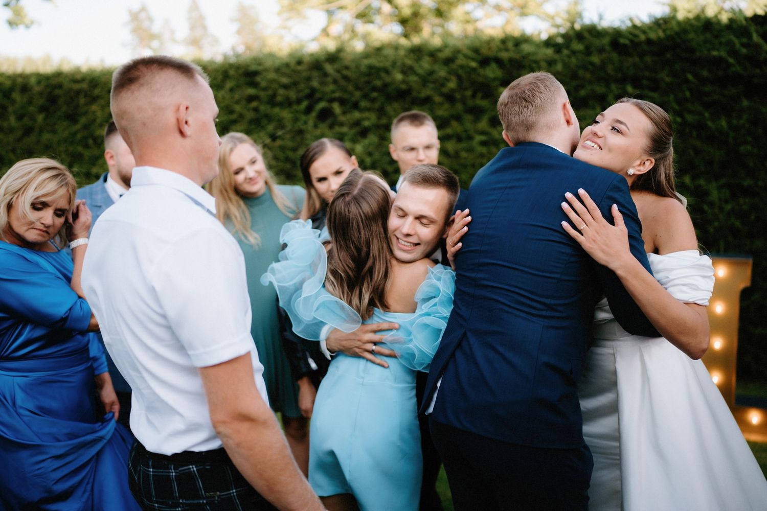 Wedding party members in navy and light blue attire sharing laughs outdoors.