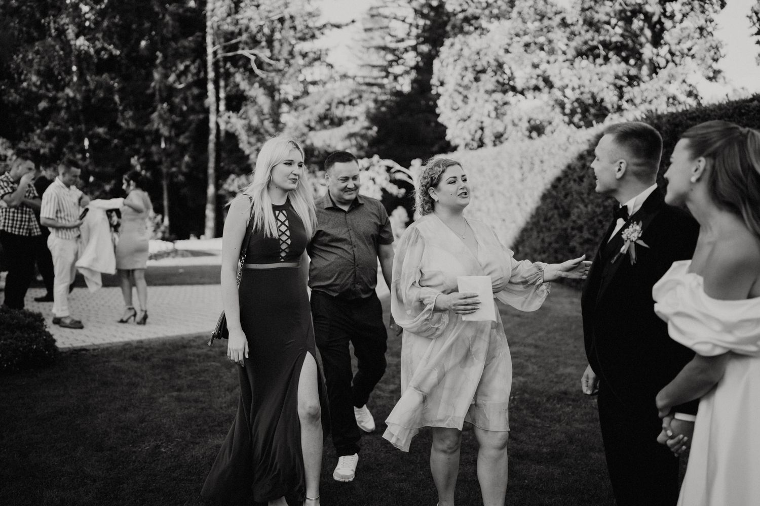 Black and white photo of wedding guests dancing and celebrating outdoors.