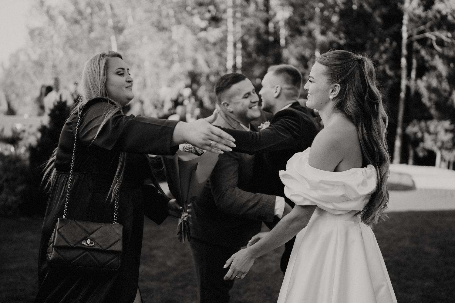 Wedding party members laughing and dancing together at an outdoor reception.