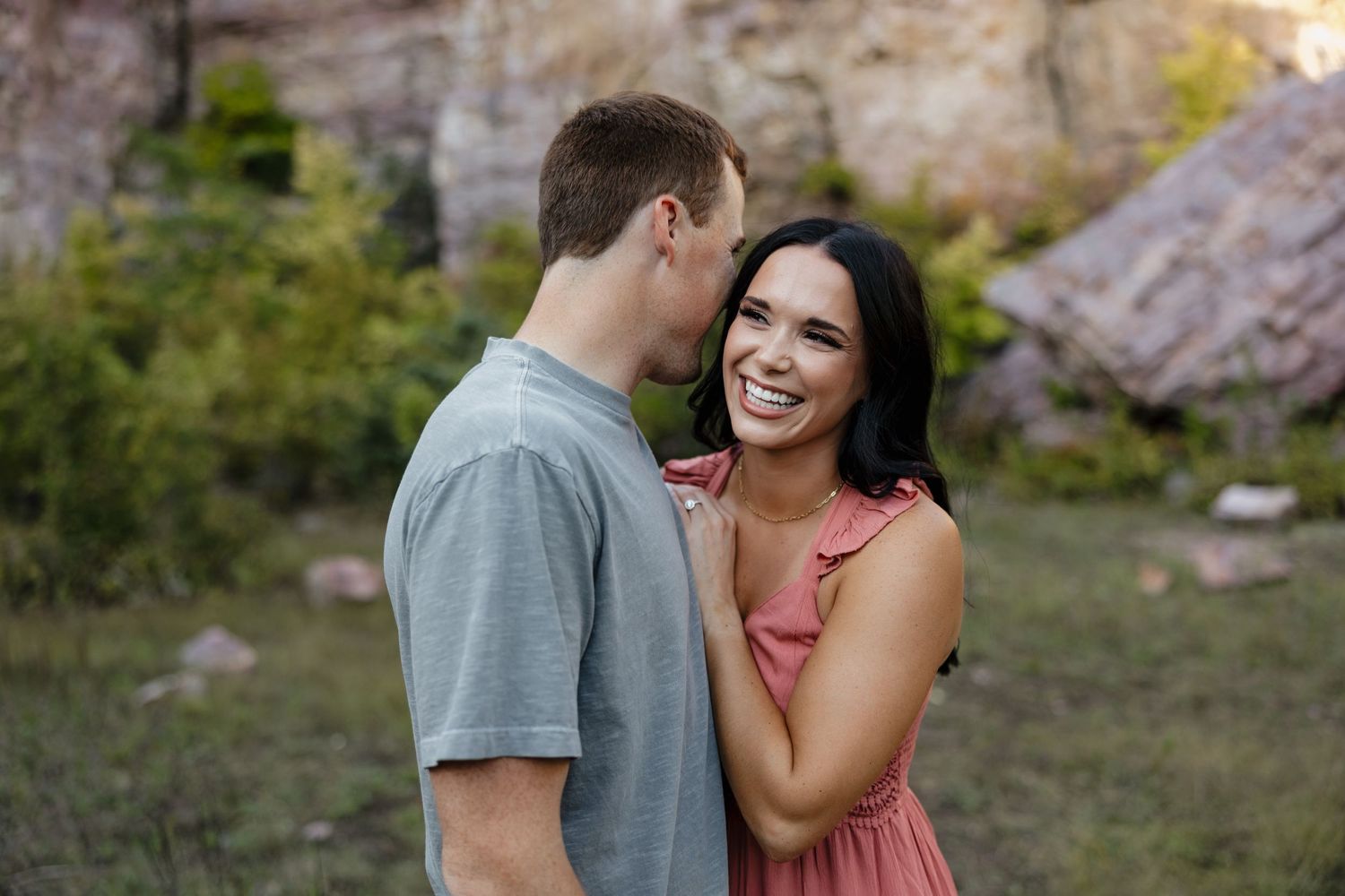 Romantic couple shares intimate moment in front of rocky cliffs at golden hour.