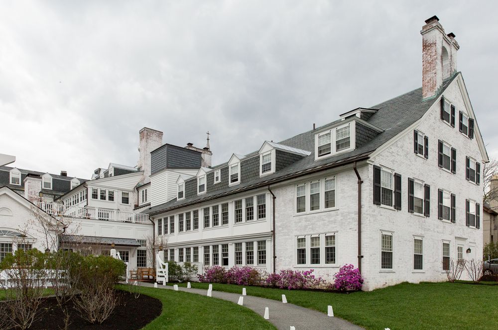 Row of classic white New England colonial houses with black shutters along coastal property.