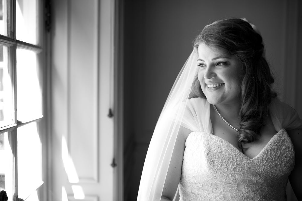 Black and white portrait of a person in a wedding veil by a window.