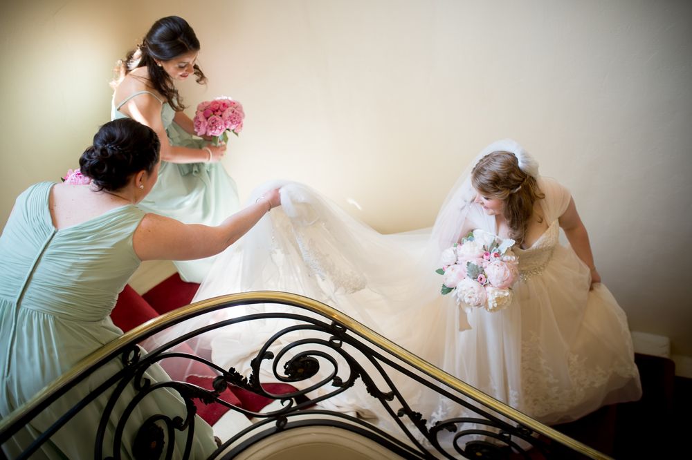 Elegant bridal preparation scene with ornate iron headboard and flowing white dress.